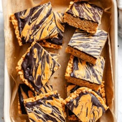Cut butterscotch rice krispie treats in a baking dish lined with parchment paper.