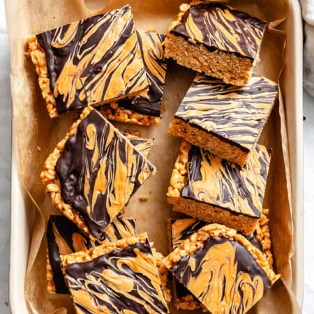Cut butterscotch rice krispie treats in a baking dish lined with parchment paper.