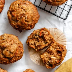 A carrot cake muffin split in half surrounded by carrot cake muffins.
