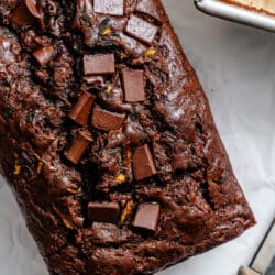 A loaf of chocolate zucchini bread topped with chocolate chunks.