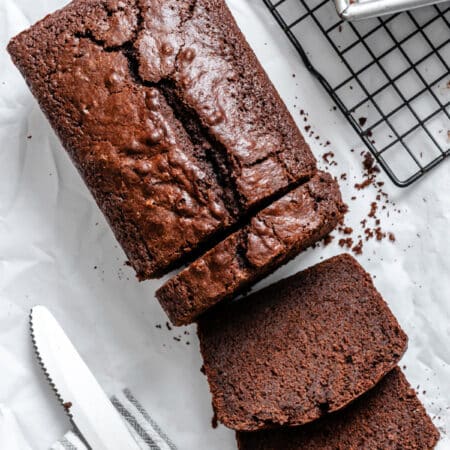 Two slices of chocolate pound cake laying down next to the loaf.