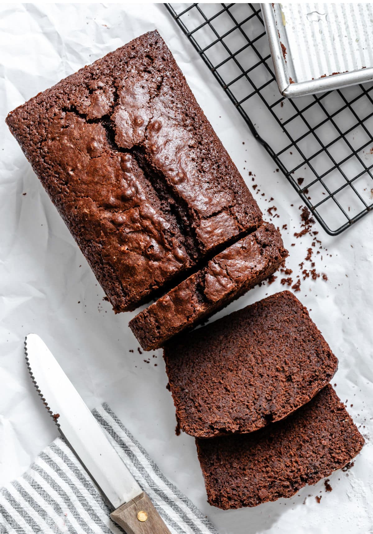 Two slices of chocolate pound cake laying down next to the loaf.
