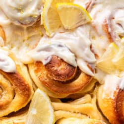 Close up photo of partially frosted lemon rolls with lemon garnish.