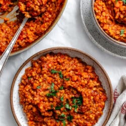 A bowl of lentil bolognese next to the pan of lentil bolognese.