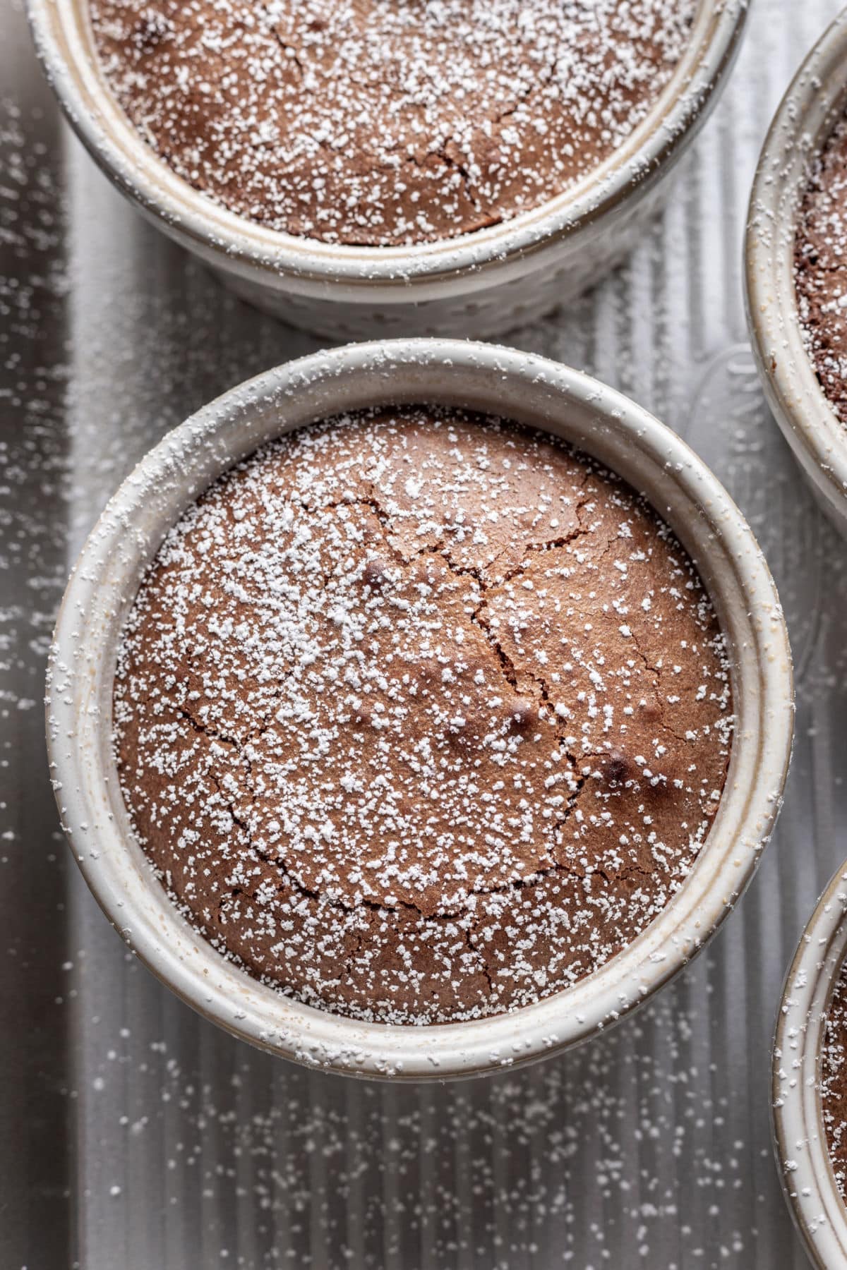 Baked chocolate lava cake in a ramekin dusted with powdered sugar.