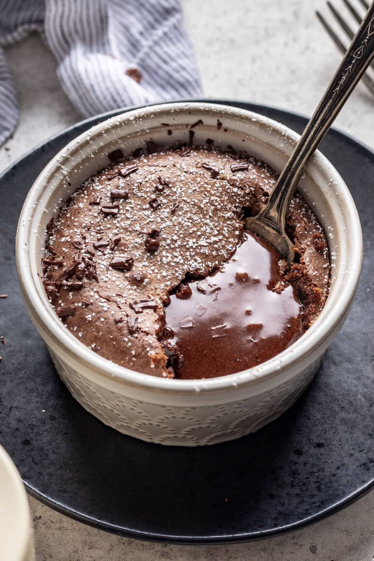 Molten Chocolate Cake Recipe A fork digging into a molten chocolate cake with chocolate pooling up around the cake.