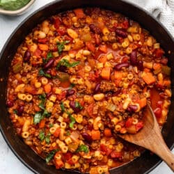 A wooden spoon in a Dutch oven of pasta e fagioli soup.