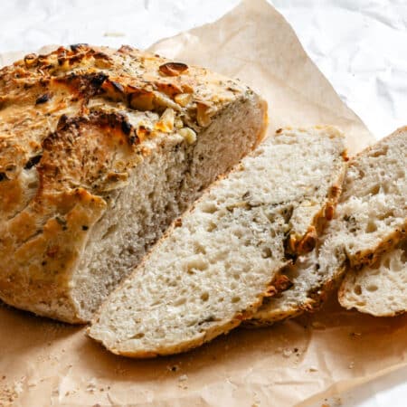 A loaf of garlic herb no knead bread with a few slices sliced.