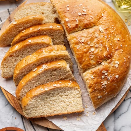 A loaf of honey oat skillet bread with slices cut from half of it.