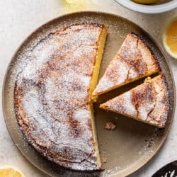 A lemon olive oil cake with two slices cut from it.