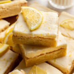 Two lemon cookie bars topped with half a slice of fresh lemon.