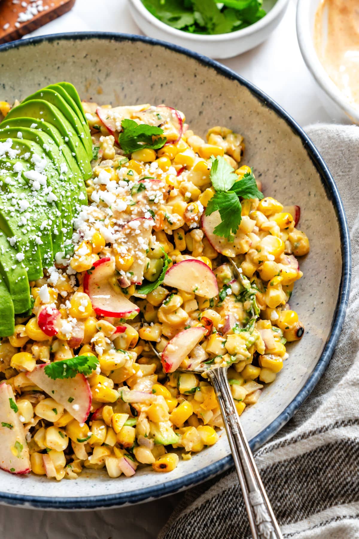 A silver spoon in a dish of Mexican street corn salad.