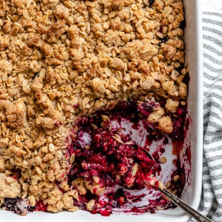 A spoon in a pan of triple berry crisp.
