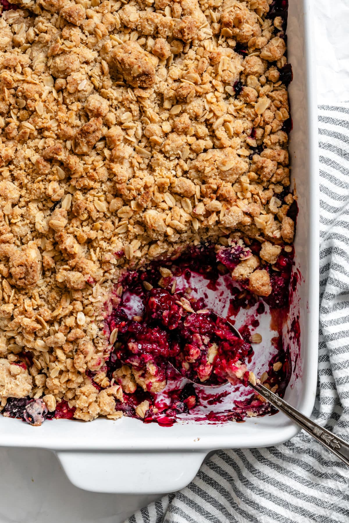 A spoon in a pan of triple berry crisp.