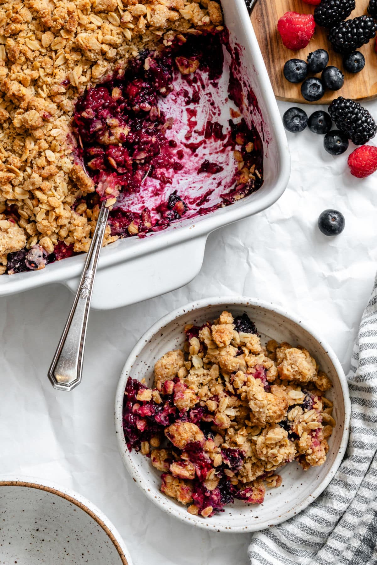 A bowl of triple berry crisp next to the pan.