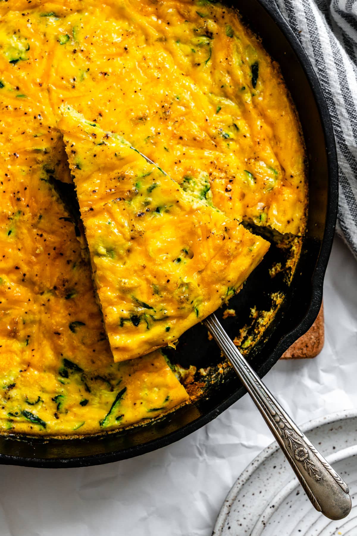 Close up of a server holding a slice of zucchini frittata in the skillet.