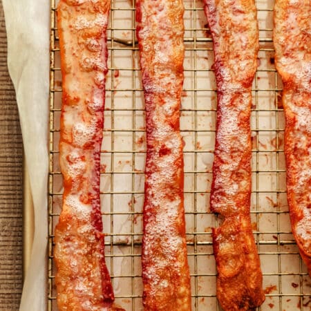 Strips of cooked bacon on a wire cooling rack in a pan.