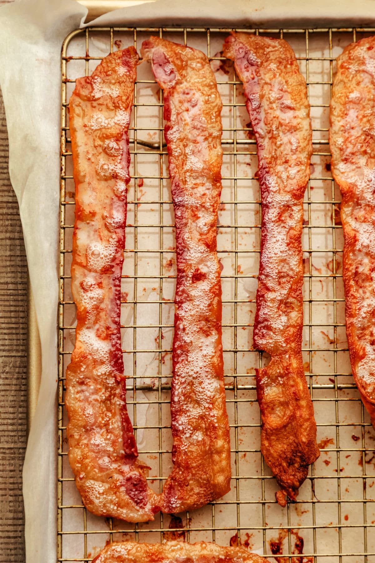 Strips of cooked bacon on a wire cooling rack in a pan.