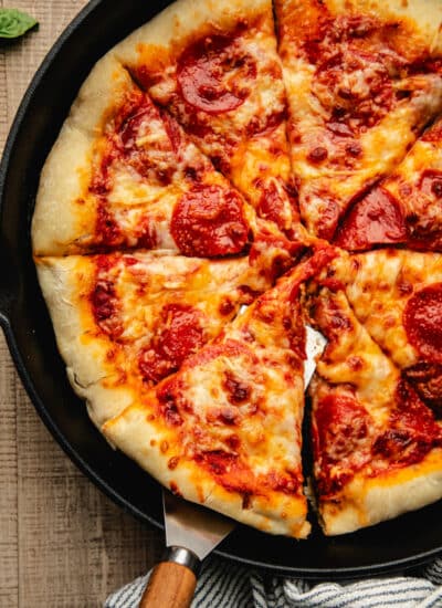 A server lifting a slice of pizza from the skillet.