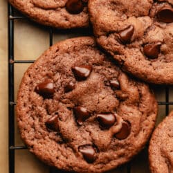 Overlapping chocolate chocolate chip pudding cookies on a wire cooling rack.