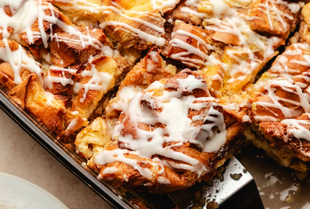 A server holding a slice of cinnamon roll bread pudding.
