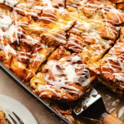 A wood handled server picking up a piece of cinnamon roll bread pudding.