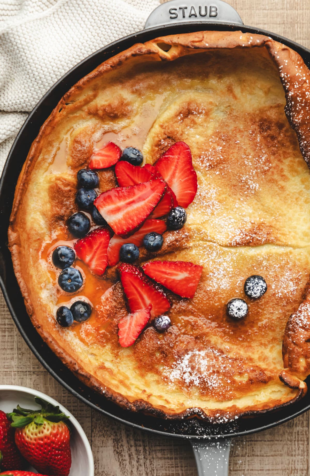 A German pancake in a skillet next to a cream linen.