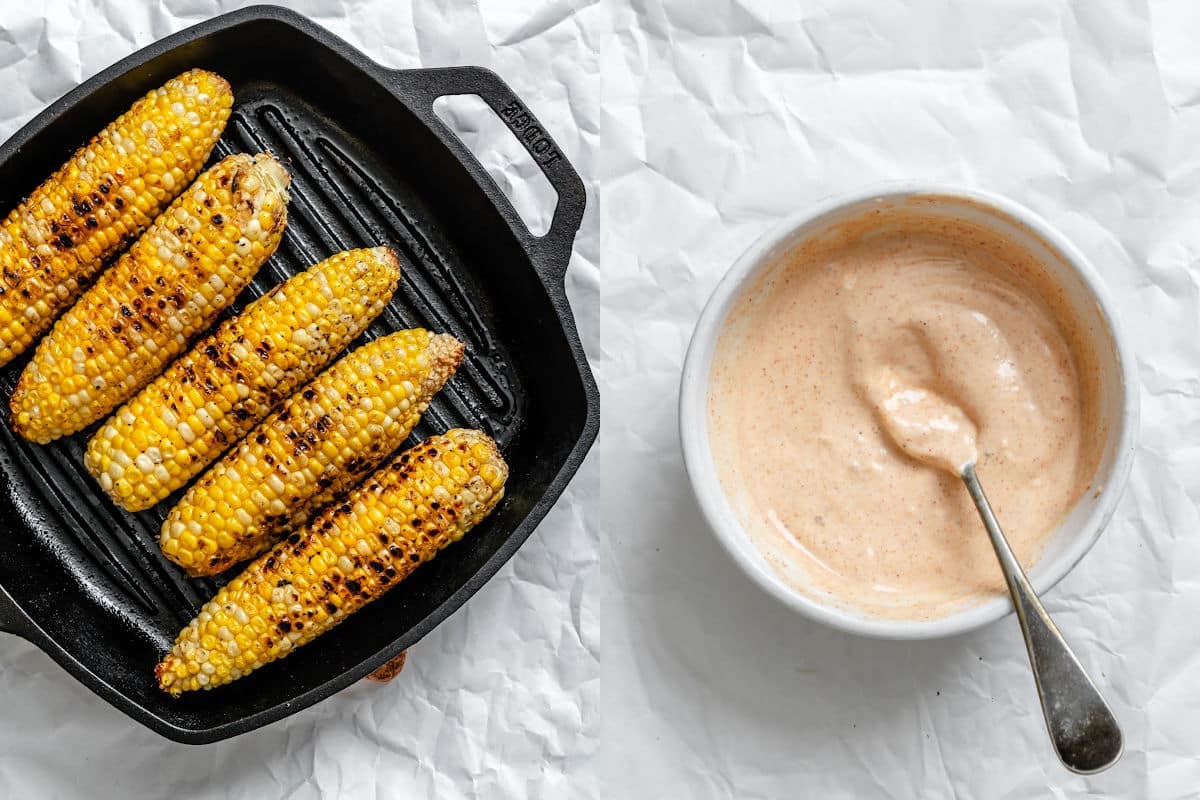 Fresh corn grilling in a grill pan next to a dish of homemade chipotle dressing.