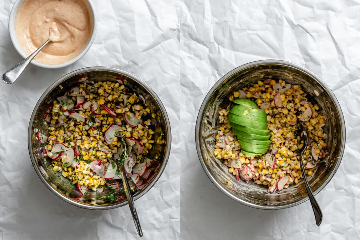 dressed Mexican street corn salad in a mixing bowl topped with fresh sliced avocado.