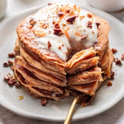 A fork cutting a bite of a stack of carrot cake pancakes.