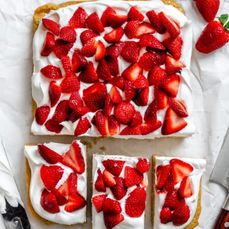 Three cut strawberry shortcake bars next to the entire pan of bars.