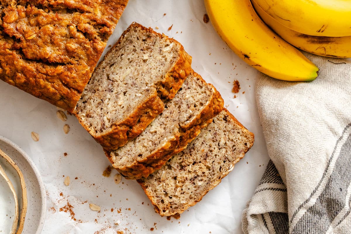 Slices of banana oatmeal bread next to bananas.