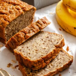 A loaf of banana oatmeal bread with three slices cut.