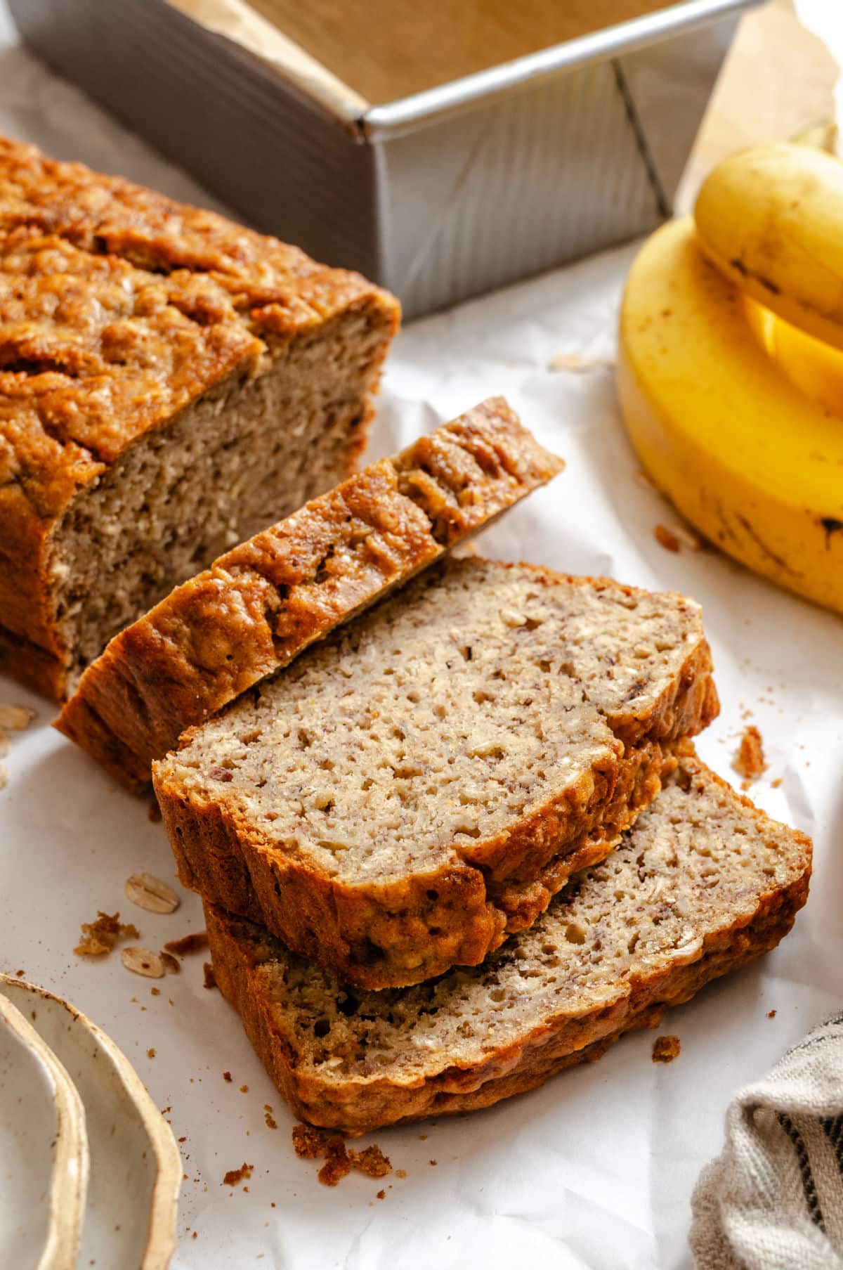 A loaf of banana oatmeal bread with three slices cut.
