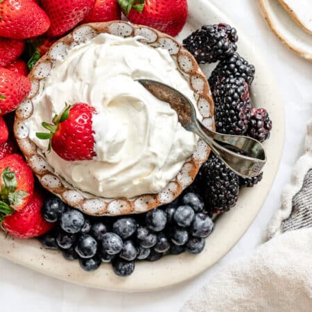 A dish of marshmallow fruit dip next to a kitchen linen.