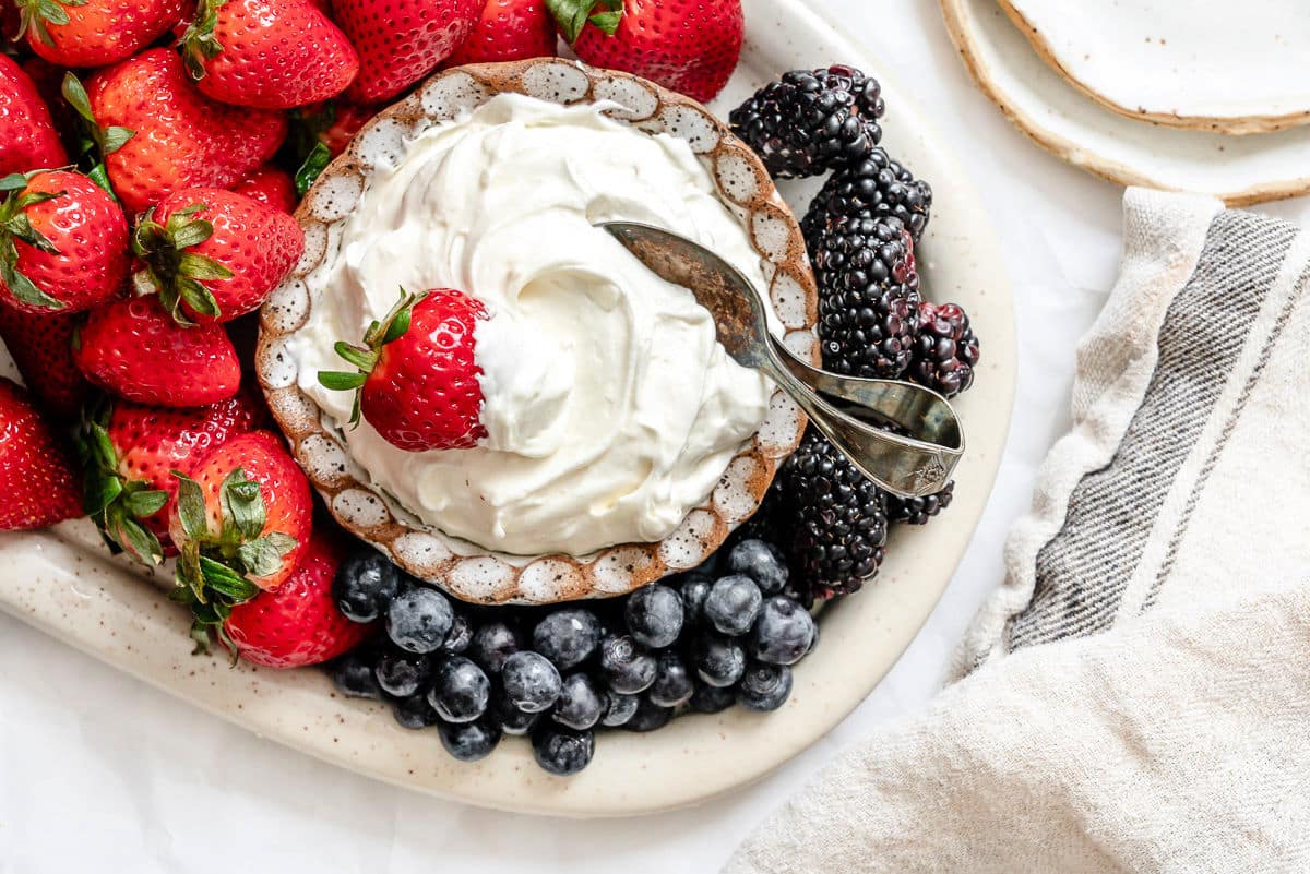 A dish of marshmallow fruit dip next to a kitchen linen.