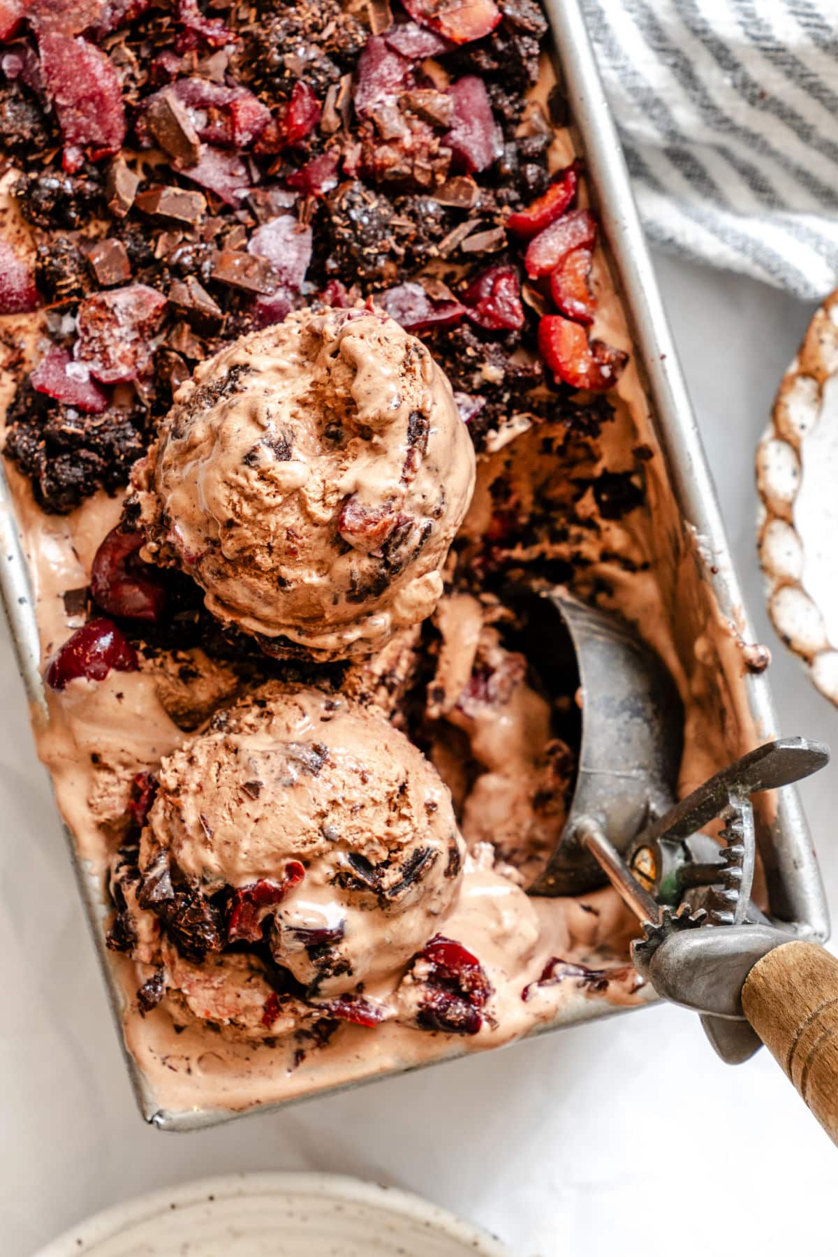 An old fashioned ice cream scoop scooping up black forest ice cream.