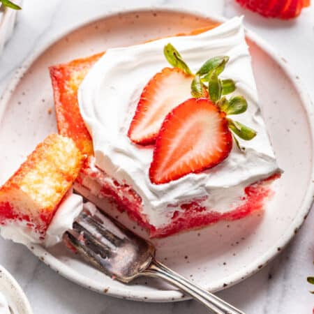 A piece of jello poke cake with a bite of the cake on a fork.