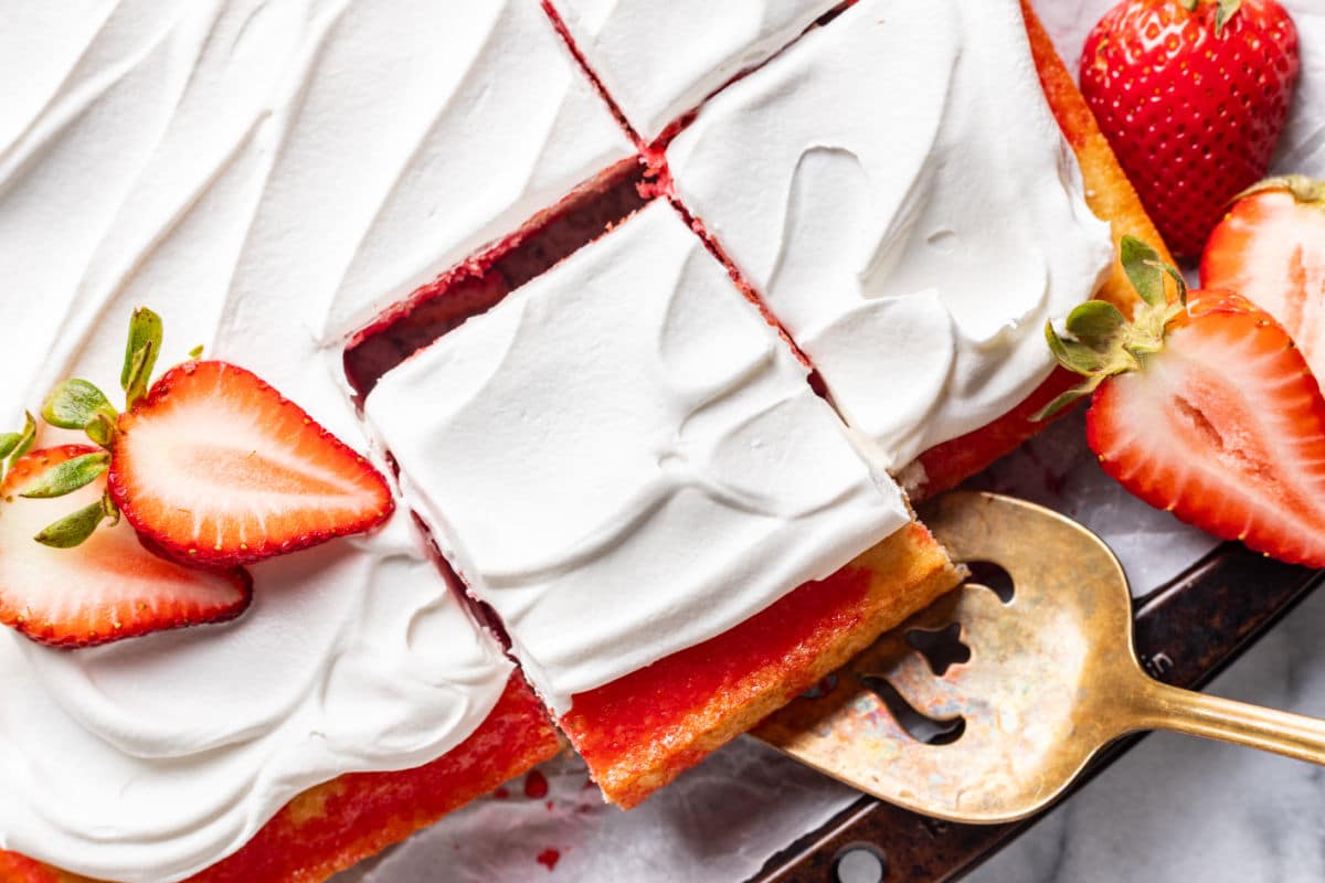 A server removing a slice of cake from a jello poke cake. 
