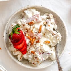 A dish of strawberry pretzel fluff topped with sliced fresh strawberries.