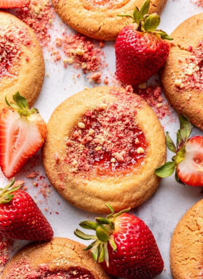Strawberry shortcake cookies surrounded by fresh strawberries.