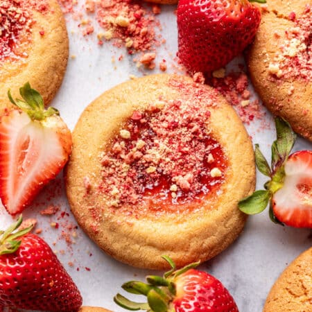 Strawberry shortcake cookies surrounded by fresh strawberries.