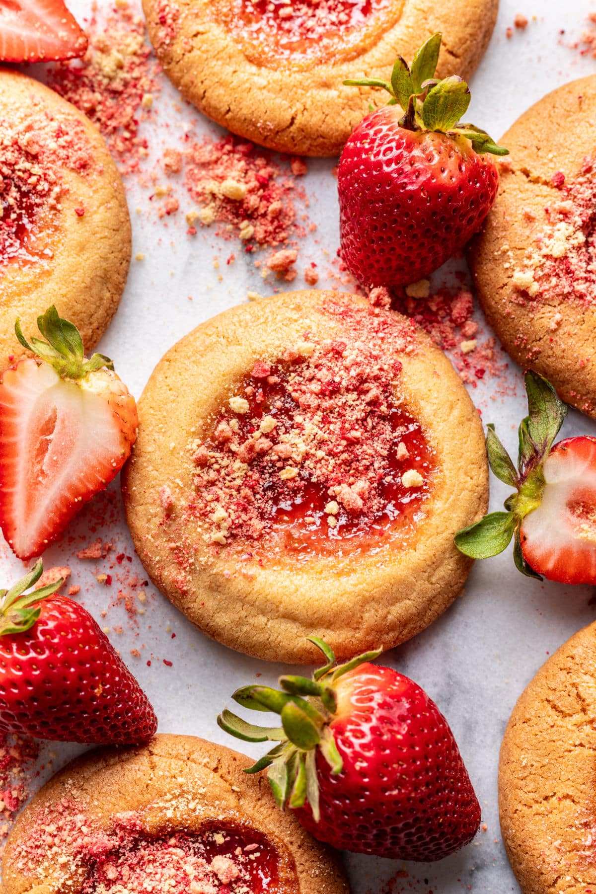 Strawberry shortcake cookies surrounded by fresh strawberries.