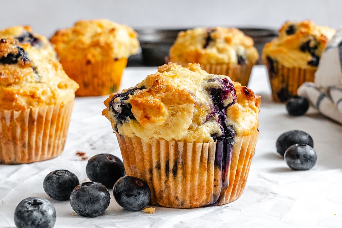 Blueberry cottage cheese muffins next to fresh blueberries.