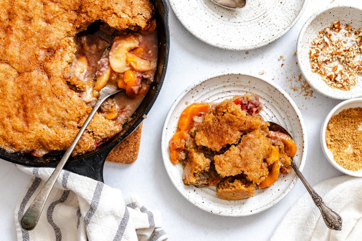 Brown Sugar Peach Cobbler Recipe A plate of brown sugar peach cobbler next to the skillet.