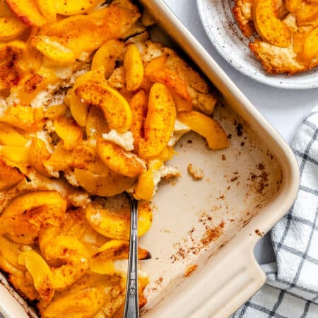 A pan of easy peach cobbler with a spoon scooping some out.