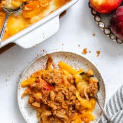 A plate of peach crumble next to the baking pan.