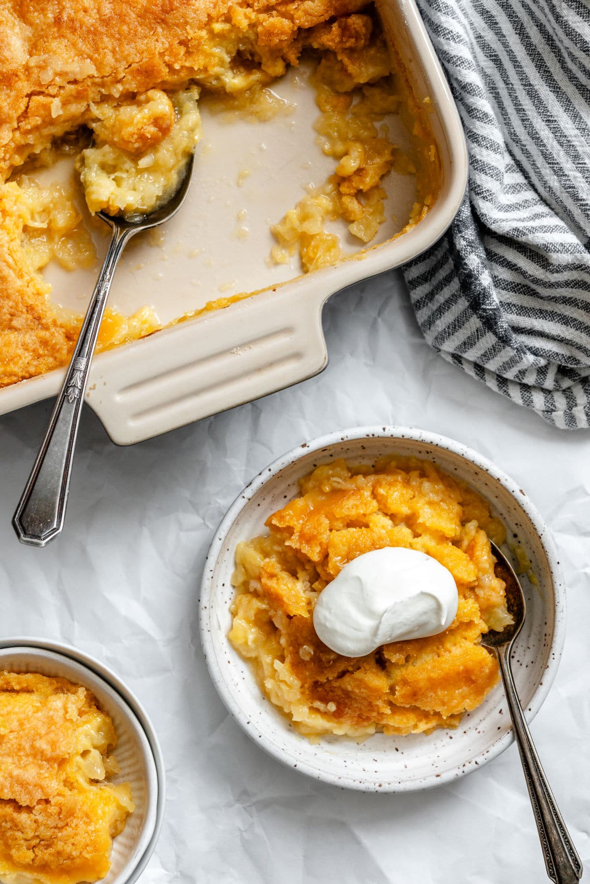Un bol de gâteau au ananas surmonté de crème fouettée à côté du plat de cuisson.