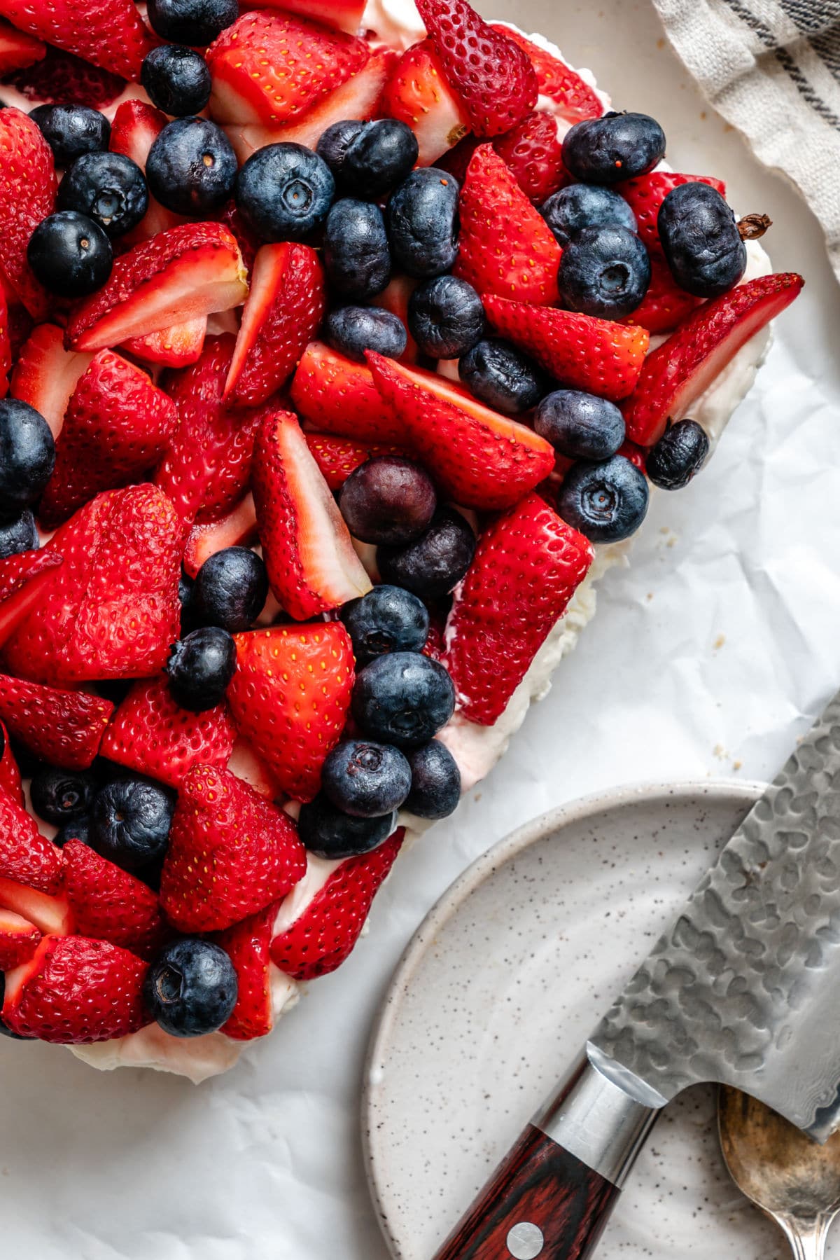 A red white and blue pretzel salad next to a knife and plates.