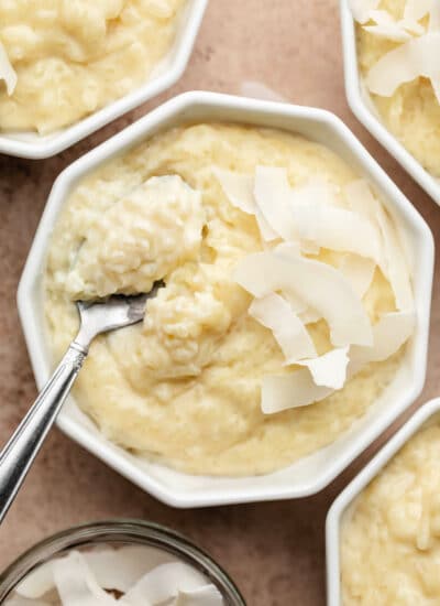 A ramekin with coconut rice pudding with a spoon holding a scoop of pudding.